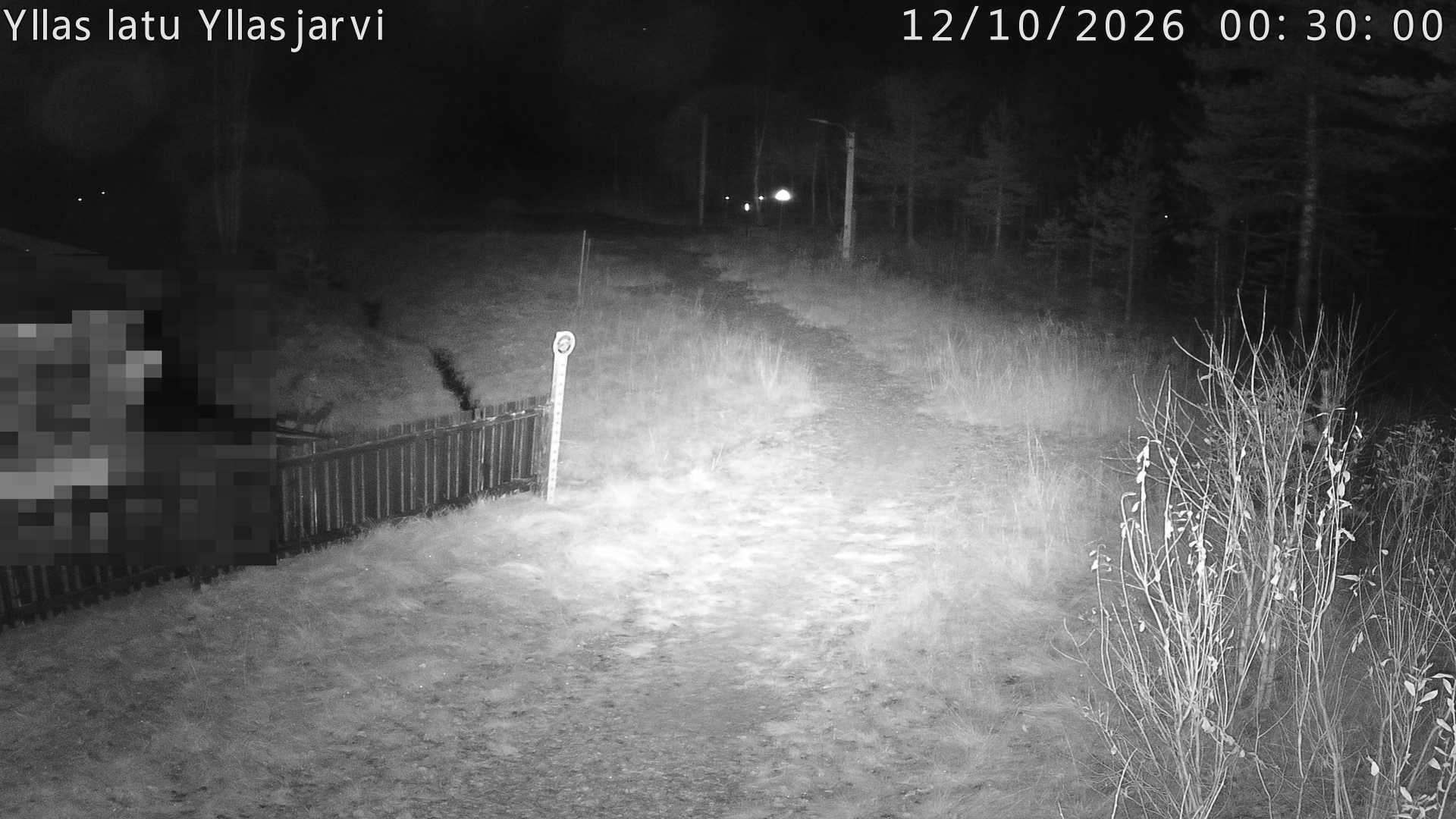 Talvella hieman mutkitteleva hiihtolatu, kesällä metsää, ja kauempana taustalla puiden yläpuolella hieman Yllästunturin rinnettä.