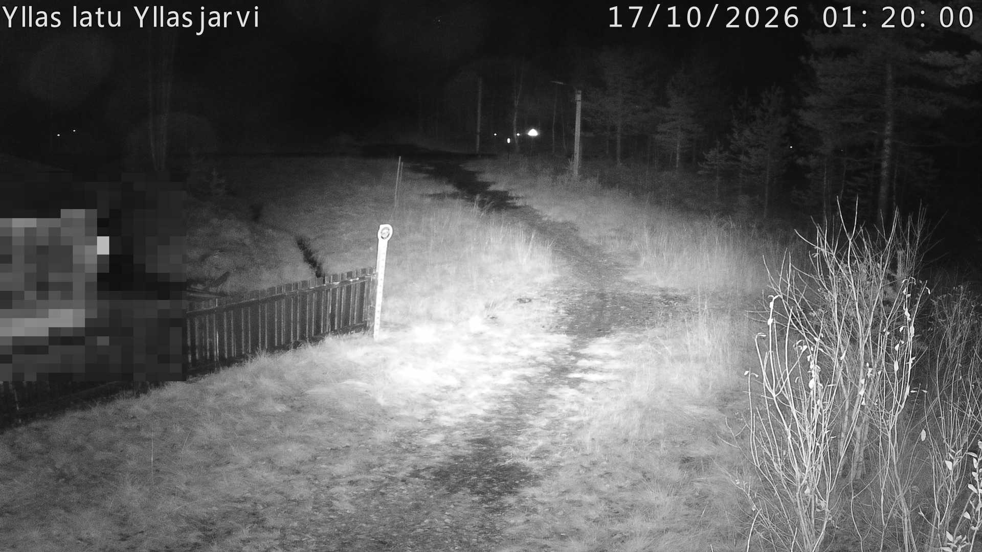 Talvella hieman mutkitteleva hiihtolatu, kesällä metsää, ja kauempana taustalla puiden yläpuolella hieman Yllästunturin rinnettä.