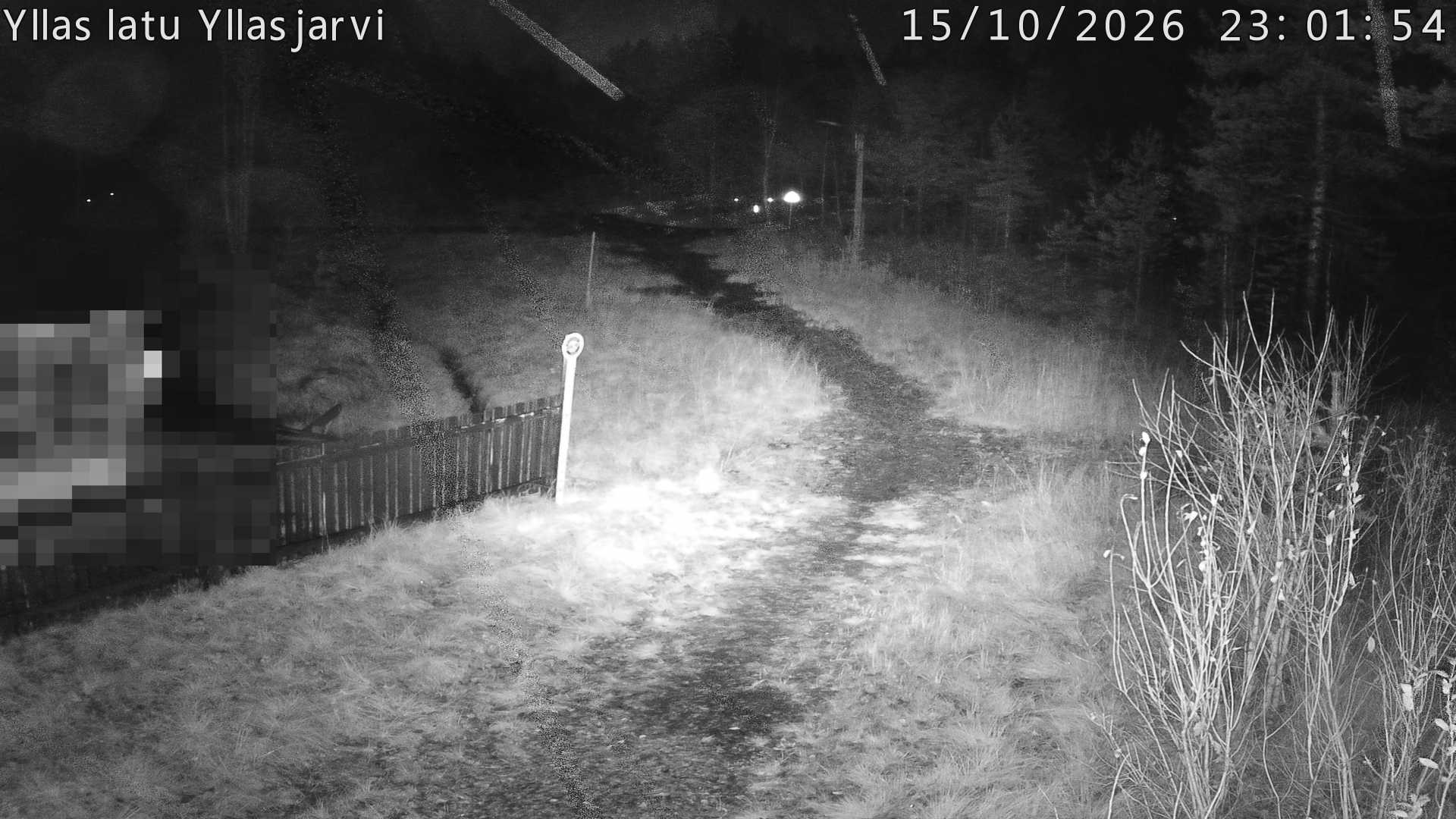 Talvella hieman mutkitteleva hiihtolatu, kesällä metsää, ja kauempana taustalla puiden yläpuolella hieman Yllästunturin rinnettä.