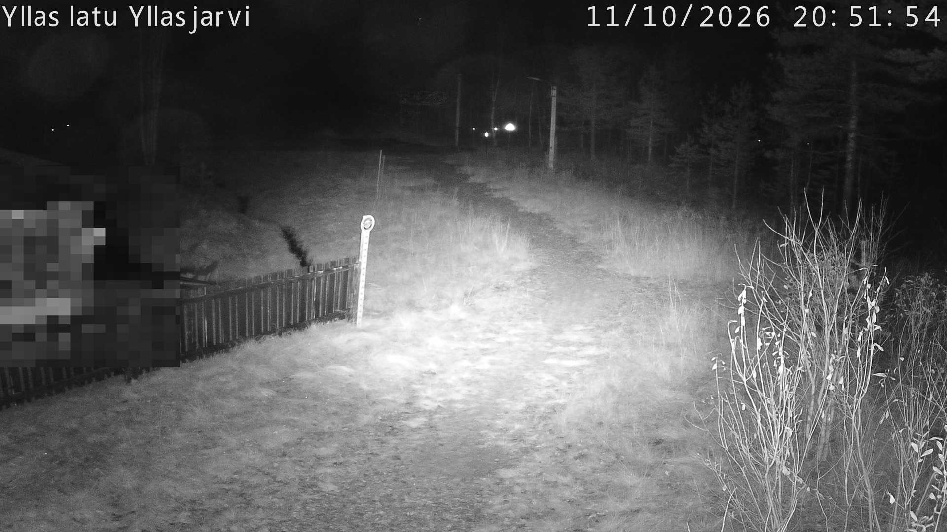 Talvella hieman mutkitteleva hiihtolatu, kesällä metsää, ja kauempana taustalla puiden yläpuolella hieman Yllästunturin rinnettä.